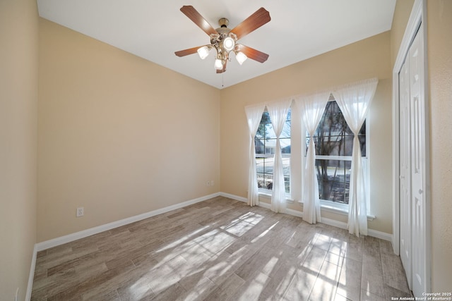 empty room featuring ceiling fan, baseboards, and wood finished floors