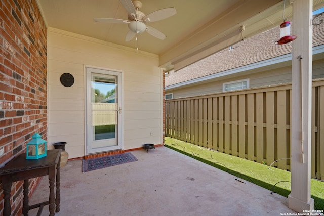 entrance to property with brick siding, fence, a ceiling fan, and a patio area