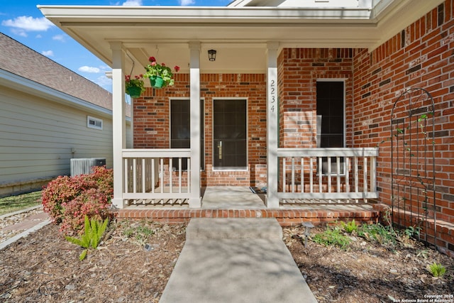 property entrance with brick siding, central AC unit, and covered porch