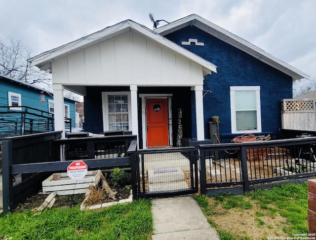 view of front of property featuring a porch, a gate, a fenced front yard, and board and batten siding