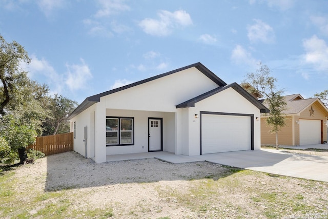 view of front of property featuring a garage, fence, driveway, and stucco siding