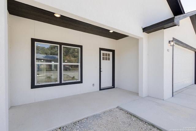 property entrance featuring an attached garage and stucco siding