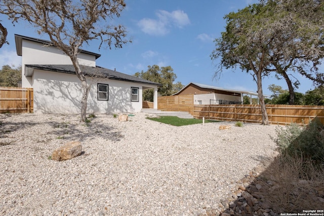 rear view of house featuring fence and stucco siding