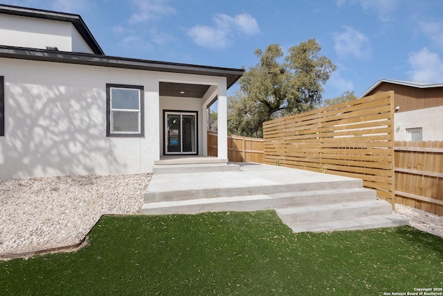 entrance to property with fence and stucco siding