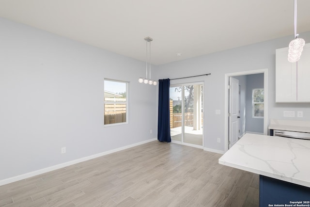 unfurnished dining area with light wood-type flooring and baseboards