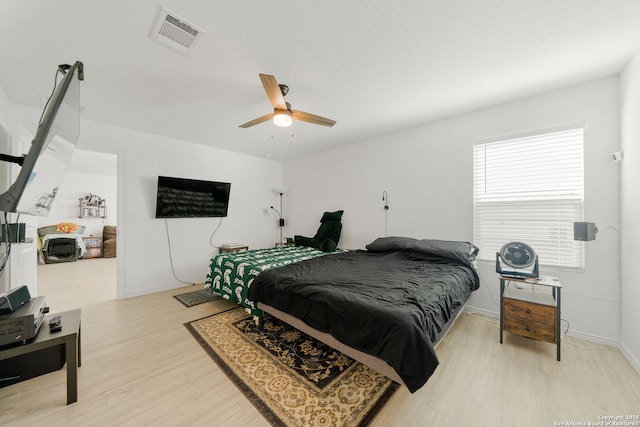 bedroom with ceiling fan, light wood finished floors, visible vents, and baseboards