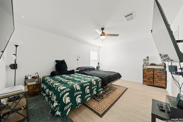 bedroom featuring light wood-style floors, ceiling fan, visible vents, and baseboards