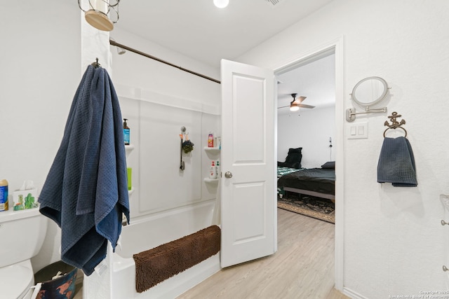 bathroom featuring toilet, a ceiling fan, a shower, and wood finished floors