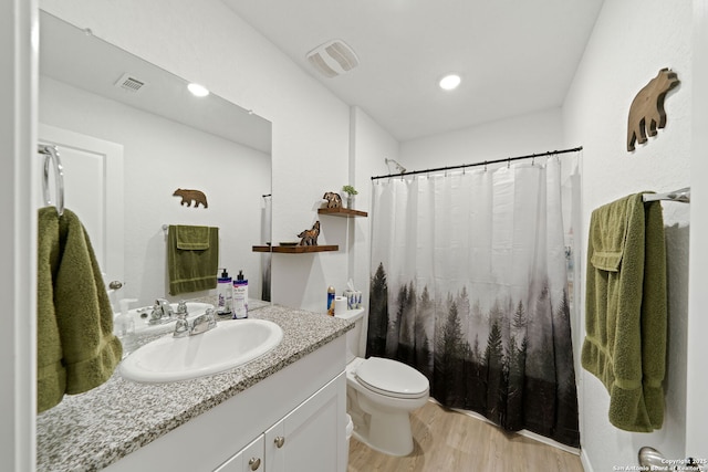 bathroom featuring curtained shower, toilet, wood finished floors, vanity, and visible vents