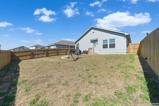 rear view of property featuring a lawn and a fenced backyard