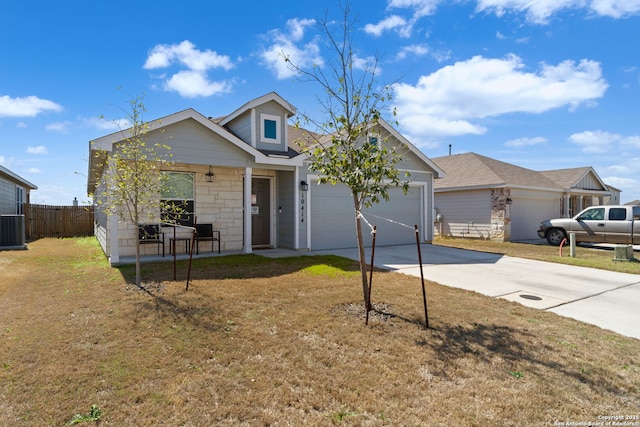 view of front of house featuring an attached garage, fence, driveway, stone siding, and a front yard