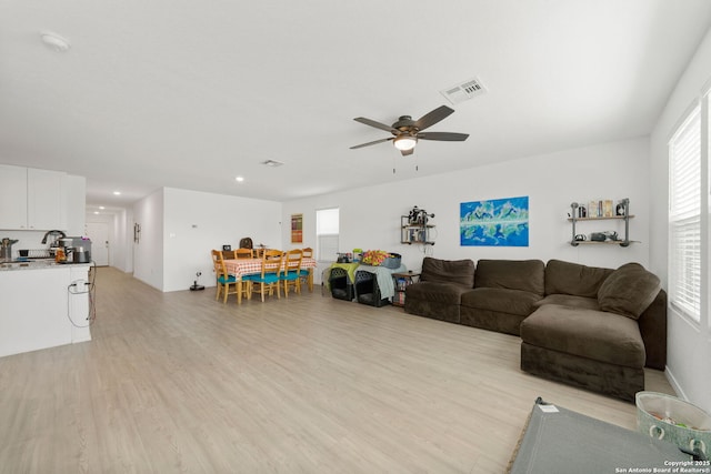 living area with light wood finished floors, ceiling fan, and visible vents