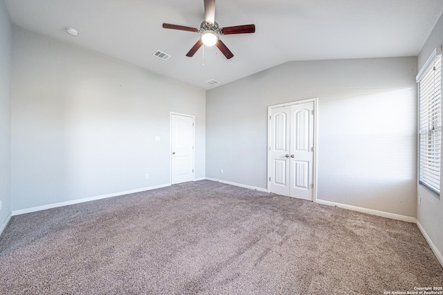empty room with carpet, visible vents, vaulted ceiling, and baseboards