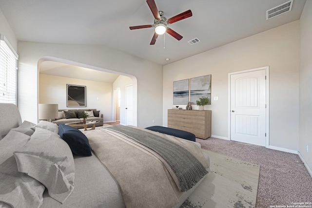bedroom with lofted ceiling, carpet, visible vents, and arched walkways