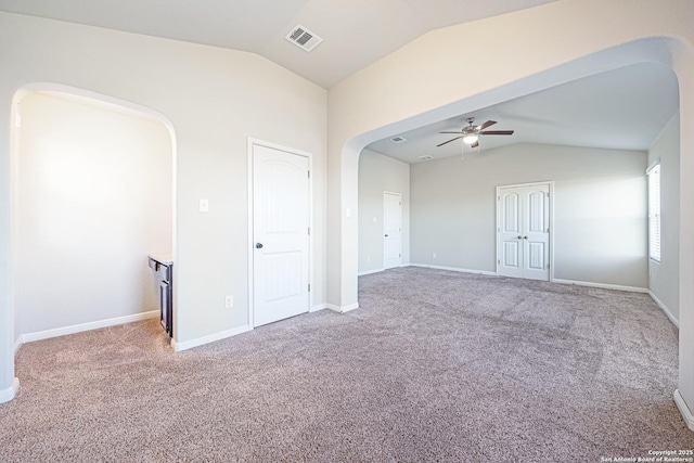 unfurnished room featuring arched walkways, carpet floors, vaulted ceiling, and visible vents