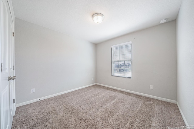 carpeted empty room featuring baseboards