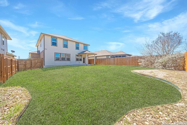 rear view of property featuring a yard and a fenced backyard