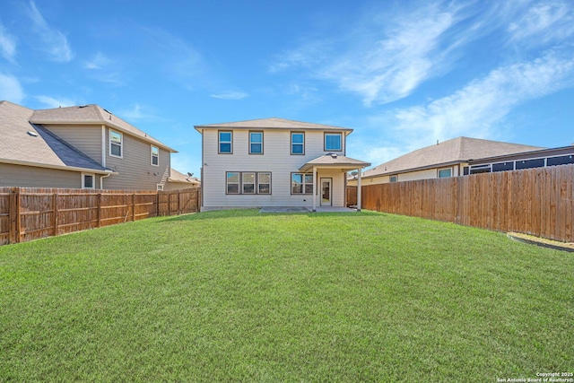 back of house with a lawn and a fenced backyard