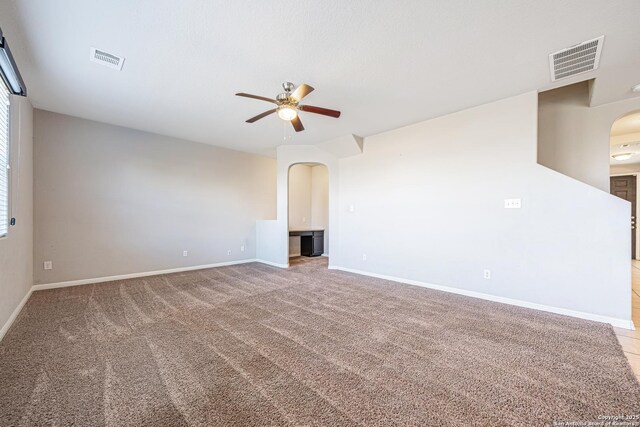 unfurnished living room with baseboards, visible vents, arched walkways, and a ceiling fan