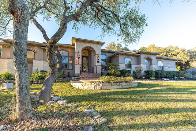 view of front of property featuring stone siding, a front yard, and stucco siding