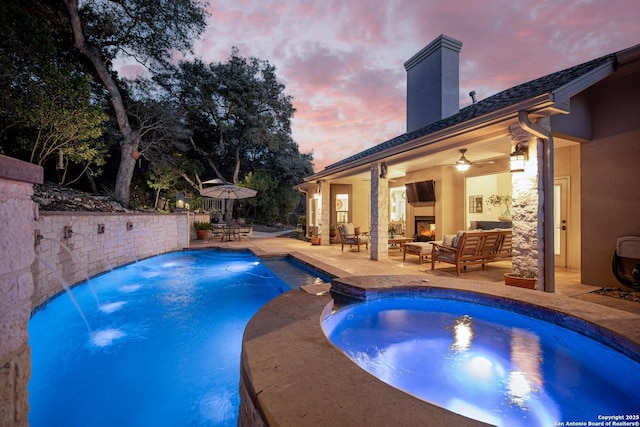 view of swimming pool featuring a patio area, an outdoor living space with a fireplace, and a pool with connected hot tub