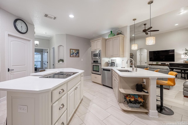 kitchen featuring arched walkways, a breakfast bar area, appliances with stainless steel finishes, open floor plan, and a sink