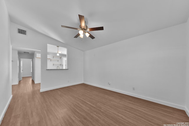 empty room with ceiling fan, wood finished floors, visible vents, baseboards, and vaulted ceiling