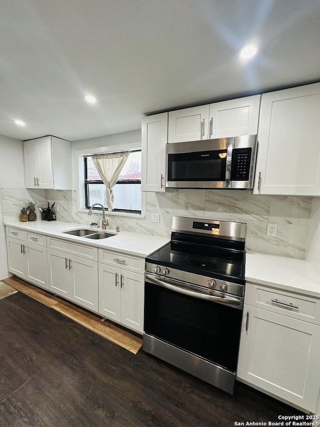 kitchen featuring white cabinets, dark wood-type flooring, a sink, stainless steel appliances, and backsplash