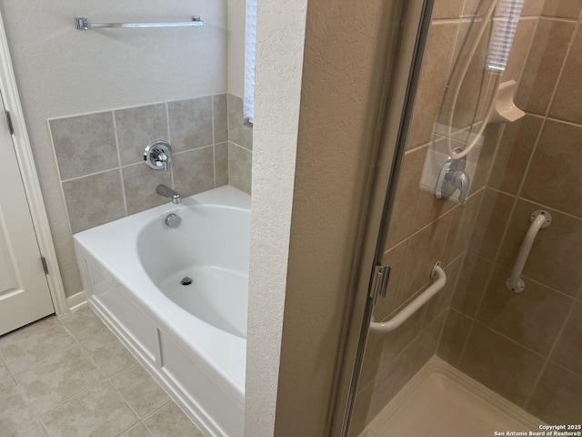 bathroom with a garden tub, a textured wall, a shower stall, and tile patterned floors