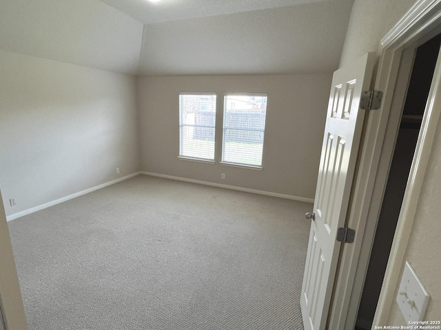 empty room with carpet floors, lofted ceiling, and baseboards