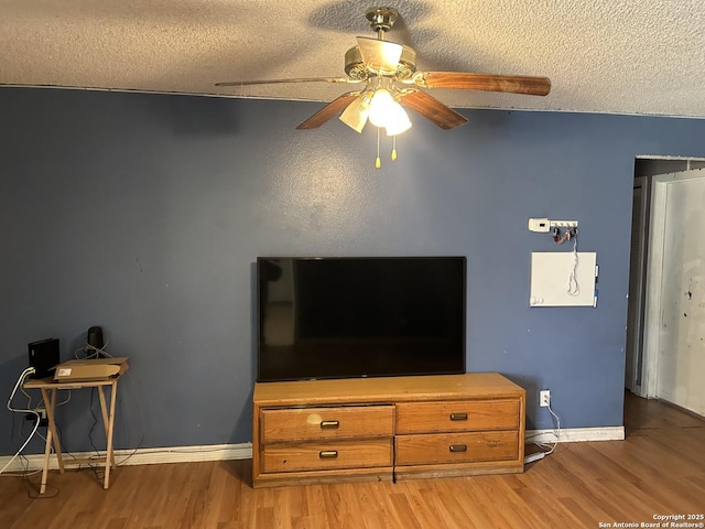 living area featuring a ceiling fan, baseboards, a textured ceiling, and light wood finished floors