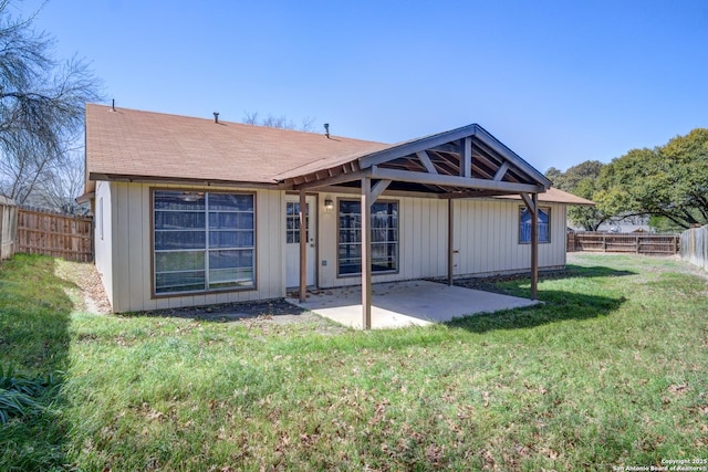 rear view of house with a patio area, a yard, and a fenced backyard