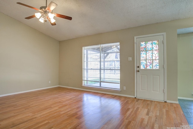 foyer entrance with a textured ceiling, light wood finished floors, a ceiling fan, and baseboards