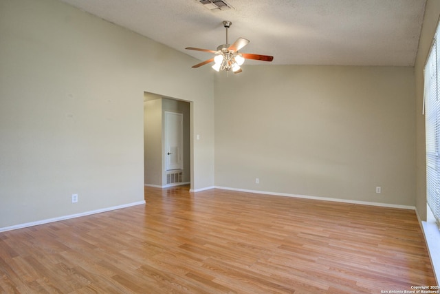 spare room featuring lofted ceiling, baseboards, visible vents, and light wood-style floors