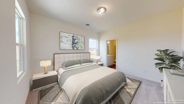 carpeted bedroom featuring visible vents, connected bathroom, and baseboards