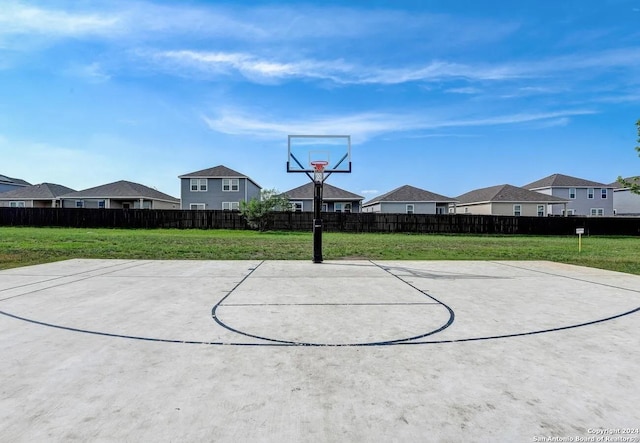 view of sport court featuring a lawn, fence, and a residential view