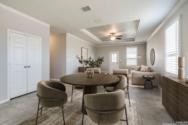 dining space with a ceiling fan, a raised ceiling, visible vents, and crown molding