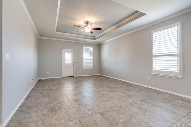 spare room with ceiling fan, crown molding, a tray ceiling, and baseboards