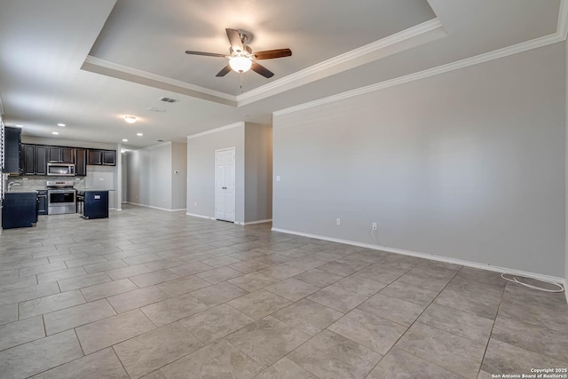 unfurnished living room featuring ornamental molding, ceiling fan, a tray ceiling, and baseboards