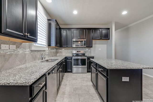 kitchen with tasteful backsplash, a kitchen island, appliances with stainless steel finishes, light stone counters, and a sink