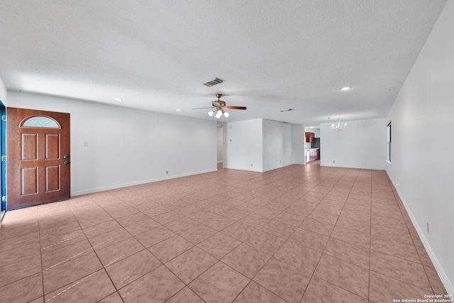 unfurnished living room featuring visible vents, a textured ceiling, baseboards, and ceiling fan with notable chandelier