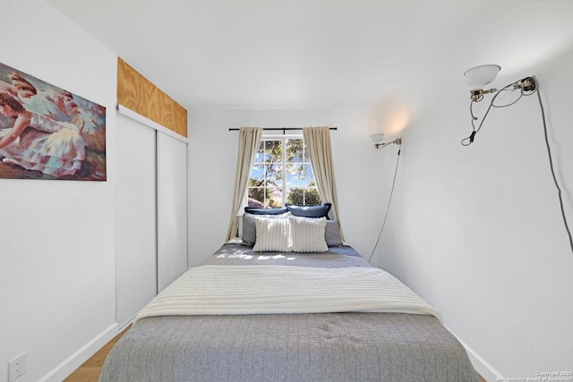 bedroom with baseboards, a closet, and wood finished floors