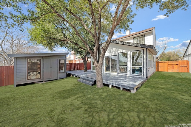 back of house with a chimney, an outdoor structure, a fenced backyard, and a wooden deck