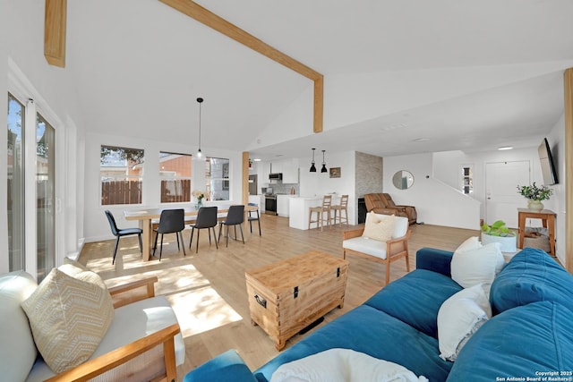 living area featuring high vaulted ceiling, beam ceiling, and light wood-style flooring