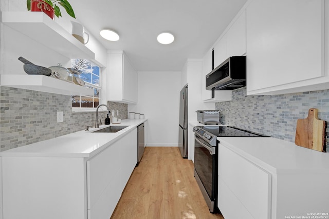 kitchen featuring open shelves, stainless steel appliances, light countertops, white cabinetry, and a sink