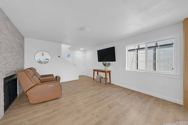 living area with a fireplace, baseboards, and wood finished floors