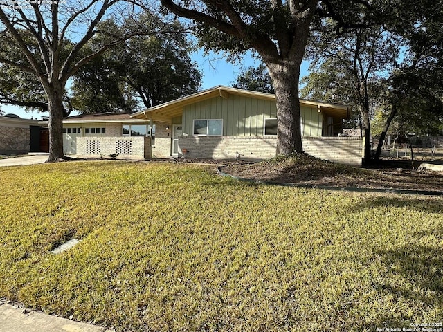 ranch-style home with an attached garage, a front lawn, board and batten siding, and brick siding