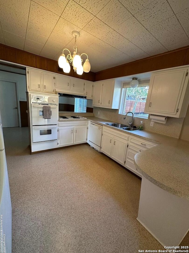 kitchen featuring a notable chandelier, white appliances, a sink, white cabinetry, and light countertops