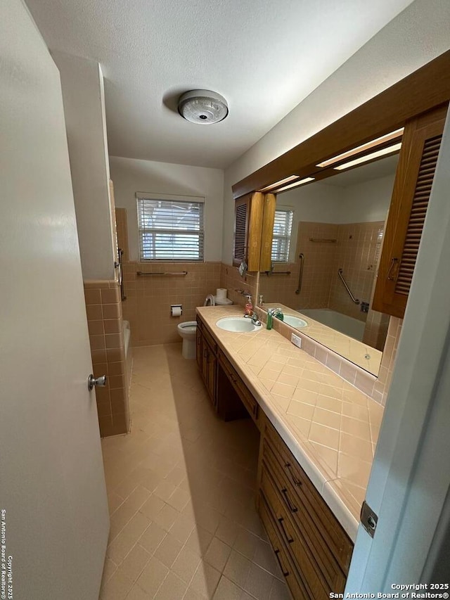 bathroom featuring toilet, a wealth of natural light, a textured ceiling, and tile walls