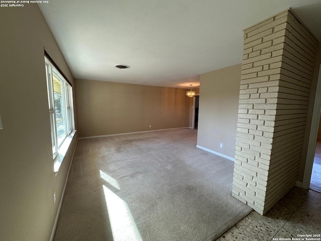 empty room featuring visible vents, light carpet, baseboards, and an inviting chandelier